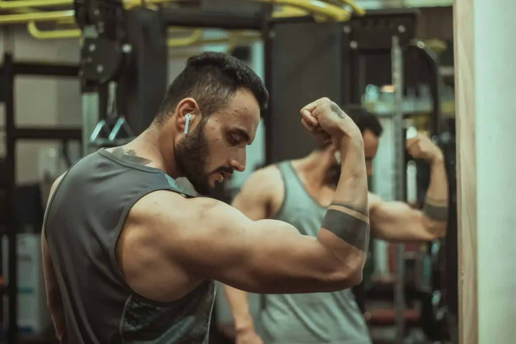 Homem musculoso fazendo flexão de bíceps na academia
